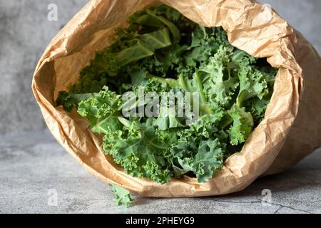 Grünkohl in einer braunen Papiertüte. Umweltfreundliches, nachhaltiges, biologisch abbaubares, kunststofffreies Verpackungskonzept Stockfoto