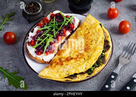 Gebratenes Omelett gefüllt mit Pilzen und Sandwich mit gegrillten Paprika und karamellisierten Zwiebeln Stockfoto