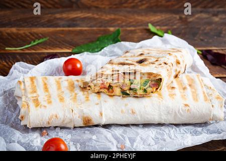 Köstliches Hähnchen-Shawarma-Sandwich mit Salat und Käse auf Holzhintergrund Stockfoto