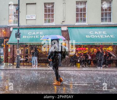 Ein Fußgänger navigiert sich durch den starken Regen im Londoner Soho. Stockfoto