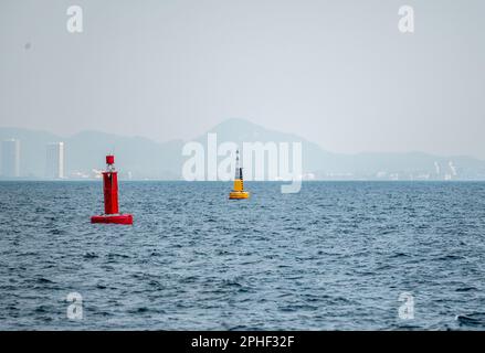 Rote Marine-Boje im Fairway. Navigationsschilder. Schiff zum Hafen eskortieren. Schwimmende gelbe Navigationsboje auf blauem Meer. Seesignalboje. Navigationa Stockfoto