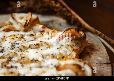 Eine frisch zubereitete Pizza mit geschmolzenem Käse steht auf einem Holztisch und ist zum Genießen bereit Stockfoto