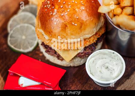 Eine köstliche Mahlzeit mit Hamburger, pommes frites und Krautsalat, serviert auf einer rustikalen Holzplatte Stockfoto