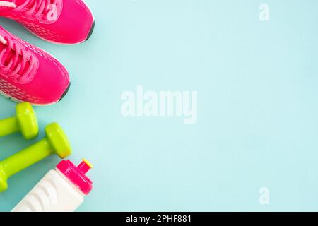 Kurzhanteln, Turnschuhe, Maßband, Wasserflasche und Notizblock auf blau. Stockfoto