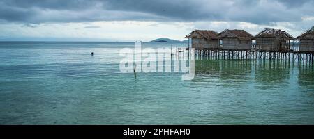 Alte zerstörte Wasserhäuser an der Küste des Dorfes Saporkren Waisai, Raja Ampat, wolkiger Himmel im Hintergrund Stockfoto