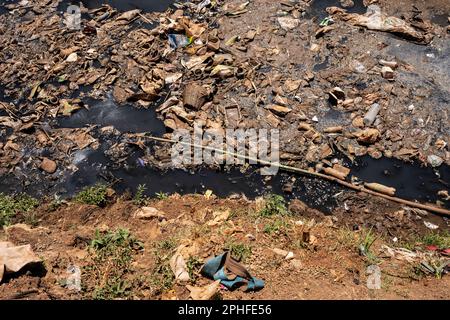 Blick auf einen verschmutzten Fluss, der durch Kibera Slum, Nairobi, Kenia fließt. Kibera ist der größte Slum Afrikas und einer der größten der Welt. Dort leben schätzungsweise 1 Millionen Menschen, die in extremer Armut leben. Eine große Mehrheit der Menschen hat keinen Zugang zu Grundversorgung und medizinischer Versorgung: Nur etwa 20 % der Kibera verfügen über Elektrizität, und das Wasser, das seine Hütten erreicht, ist nicht sauber und verursacht Typhus und Cholera. In den meisten Kibera gibt es keine Toiletten. Die Arbeitslosenquoten sind hoch, und die meisten Menschen können sich keine Bildung für ihre Kinder leisten. Stockfoto