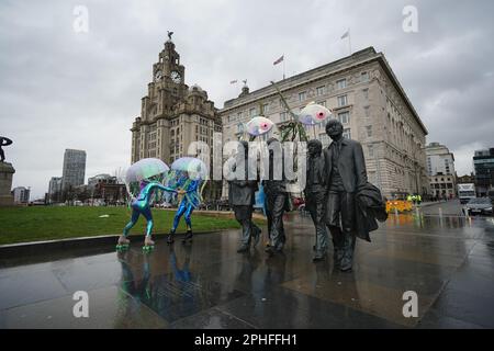 Bei der Eröffnung des Eurovision Eurofestivals im British Music Experience in Liverpool laufen auf Rollschuhen als Quallen verkleidete Künstler um die Beatles-Statue. Das zweiwöchige Festival, das aus 25 Kommissionen bestehen wird - davon 19 Kooperationen zwischen britischen und ukrainischen Künstlern - wird die Stadt im Vorfeld des Eurovision Song Contest übernehmen, während Fans aus der ganzen Welt nach Liverpool absteigen. Foto: Dienstag, 28. März 2023. Stockfoto