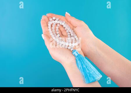 Mondstein mala-Perlen in weiblicher Hand auf blauem Hintergrund. Edelsteinstrand Stockfoto