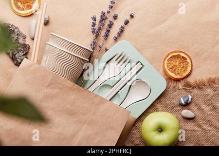 Plastikfreies, umweltfreundliches ökologisches Geschirr in wiederverwendbarem Beutel auf zerknittertem Papier. Nachhaltiger Lebensstil. Stockfoto