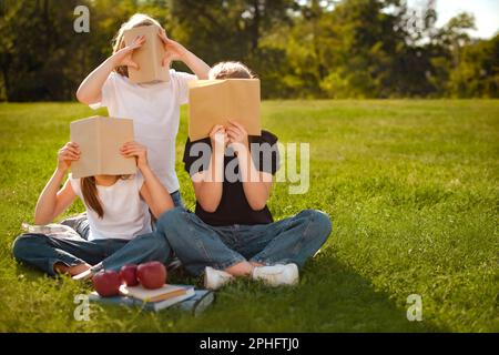 Bildungs- und Ausbildungskonzept. Kinder lesen Bücher, lernen und bereiten sich auf die Prüfung oder den Test im Park vor. Bündeln Sie Schüler mit Lehrbüchern. Stockfoto