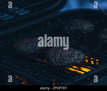 Nahaufnahme von zwei Hamburgern, die auf einem heißen Grill kochen Stockfoto