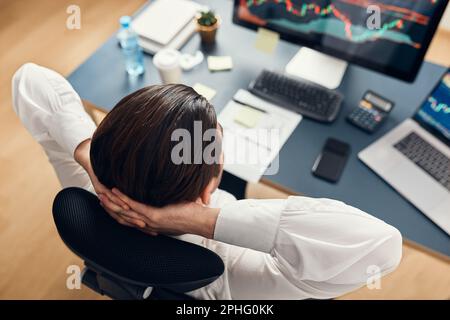 Ein Geschäftsmann, der online mit Aktien handelt. Aktienanleger, die Zahlen in Diagrammen und Diagrammen analysieren. Investorenplanung und Analyse des Börsenprofils. Mann wird Stockfoto