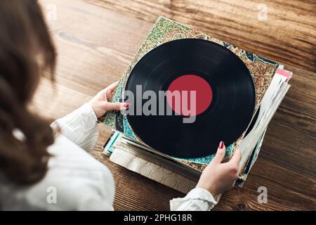 Vinyl-Schallplatten spielen. Musik von einem Vinyl-Plattenspieler hören. Retro- und Vintage-Musikstil. Frau mit analogem LP-Plattenalbum. Stapel alt Stockfoto