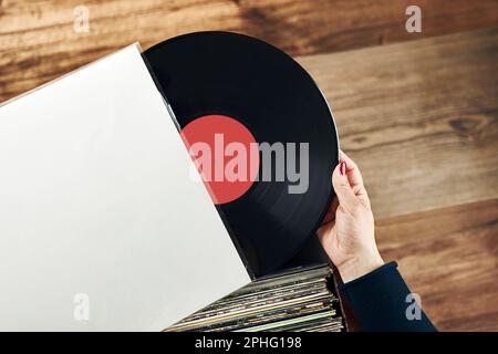 Vinyl-Schallplatten spielen. Musik von einem Vinyl-Plattenspieler hören. Retro- und Vintage-Musikstil. Frau mit analogem LP-Plattenalbum. Stapel alt Stockfoto