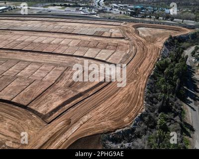 Eine Luftaufnahme einer Baustelle in einem ländlichen Gebiet, die eine von grünem Gras umgebene Stelle von Erde zeigt Stockfoto