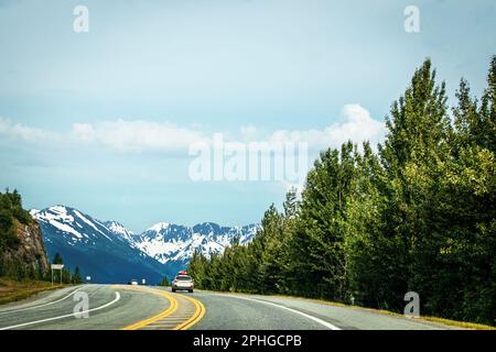 Fahrt von Anchorage nach Seward Alaska auf dem Highway 9 South auf der Kenai-Halbinsel mit schneebedeckten Bergen in der Ferne und immergrünen Bäumen auf der Halbinsel Stockfoto