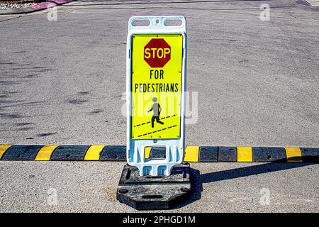 Gewichteter Stand-up-Stopp für Fußgänger Schild auf einem Parkplatz aus körnigem Beton mit gestreifter Kopie der Bodenschwelle Stockfoto