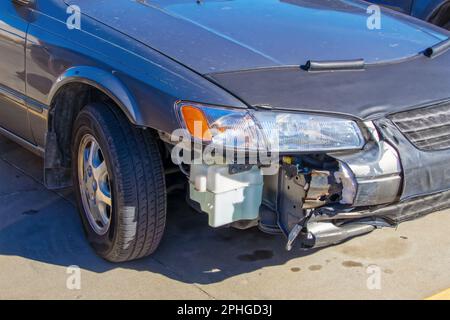 Wracked Car – silberne blaue Limousine, die den Beifahrer zeigt, der einen Unfall hatte, bei dem ein Teil des Stoßfängers fehlte, sodass Sie sehen können, wie der Stoßfänger ist Stockfoto
