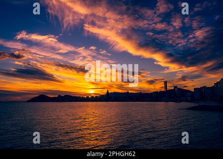 Die Wolkenkratzer hinter den Weststränden von Benidorms sind von der untergehenden Sonne beeindruckt. Stockfoto