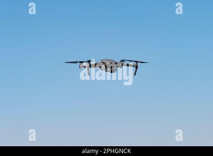 Eine fliegende Minidrohne, die Videos und Fotos im blauen Himmel aufnimmt Stockfoto