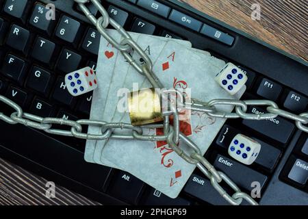 Konzept von Vorhängeschloss und Spielkarten isoliert auf der Tastatur. Konzept des Online-Glücksspiels Stockfoto