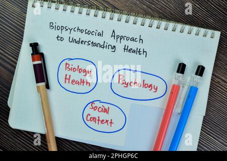 Konzept eines biopsychosozialen Ansatzes zum Verstehen von Gesundheit Schreiben auf Buch isoliert auf Holztisch. Stockfoto