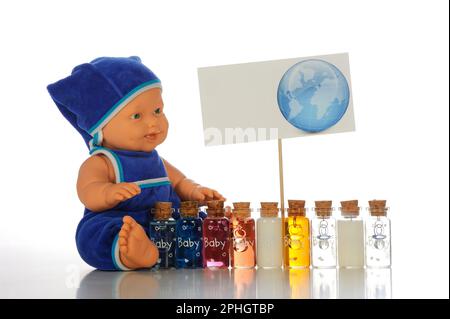 Süße kleine Puppe in blauem Overall und Hut mit bunten Flaschen auf weißem Hintergrund Stockfoto
