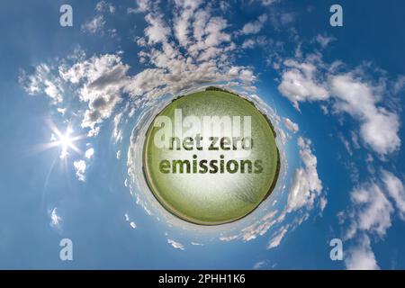Netto-Null-Emissionen Text Konzeptbild gegen grünen, winzigen Planeten in blauem Himmel mit wunderschönen Wolken, grüner, winziger Planet in blauem Himmel mit wunderschönen Wolken Stockfoto