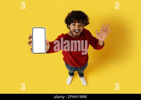 Aus dem Blickwinkel sieht man einen indianer, der Smartphone und Modell zeigt Stockfoto