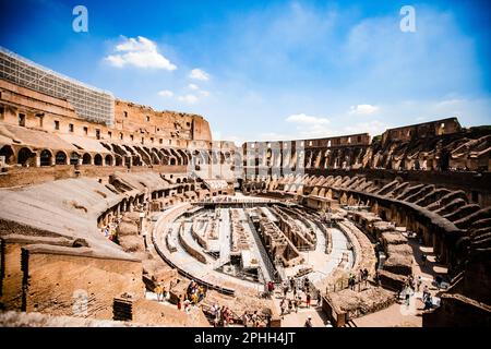 Eine Gruppe von Personen, die an einem sonnigen Tag durch die Arena des Kolosseums spazieren. Rom, Italien. Stockfoto