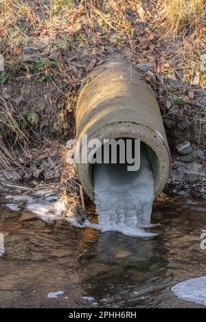 Wasserleitung mit gefrorenem Wasser in einem kleinen Bach. Stockfoto