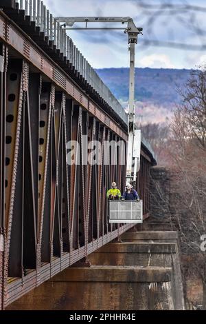 Bauarbeiter inspizieren eine Eisenbahnbrücke über den Susquehanna River von einem Korb aus. Stockfoto