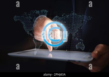 Illustrationen von Weltkarte, Copyright-Symbol und Mann mit Tablet auf dunklem Hintergrund, Nahaufnahme Stockfoto