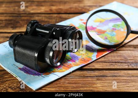 Modernes Fernglas, Lupe und Karte auf Holztisch Stockfoto