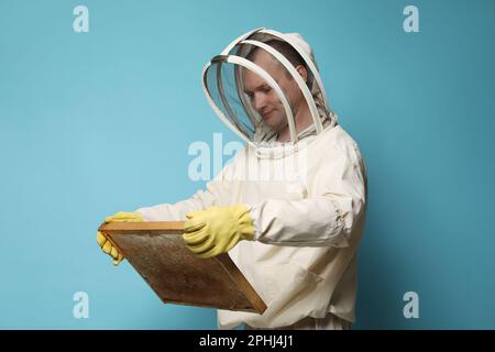 Imker in einheitlichem Bienenstockrahmen mit Wabenstruktur auf hellblauem Hintergrund Stockfoto