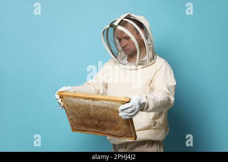 Imker in einheitlichem Bienenstockrahmen mit Wabenstruktur auf hellblauem Hintergrund Stockfoto