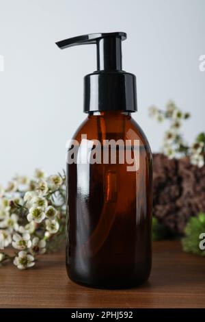 Eine Flasche hydrophiles Öl und wunderschöne Blumen auf einem Holztisch Stockfoto