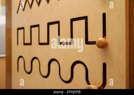 Ein hölzernes Labyrinth mit verschiedenen Linien an der Wand, Nahaufnahme. Montessori Spielzeug Stockfoto