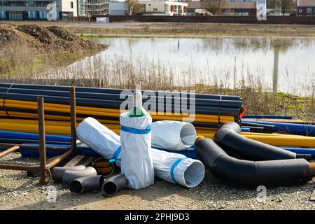 Baustelle mit Rohren in verschiedenen Farben und Größen. Gasflasche in der Mitte. Stockfoto