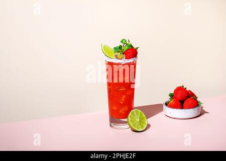 Paloma alkoholisches Cocktailgetränk mit Tequila, Grapefruit und Limettensaft, Erdbeeren, Minze und Eis im Glas mit salzhaltigem Rand. Beige rosa Vanille Backgr Stockfoto