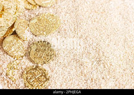 Eine vergrabene Piratenschatzmünze im Sand an einem Strand Stockfoto