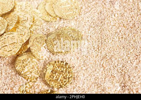 Eine vergrabene Piratenschatzmünze im Sand an einem Strand Stockfoto