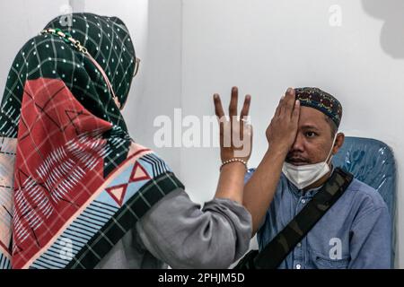 Bogor, Indonesien. 27. März 2023. Ein indonesischer Einwohner lässt seine Augen am 27. März 2023 bei Untersuchungen in der Ainun Cahaya Medika Augenklinik in Bogor Regency, Indonesien, untersuchen. Das Programm zielt darauf ab, benachteiligten Gemeinschaften zu helfen, Augengesundheitsdienste zu erhalten, um die Blindheit aufgrund von Katarakt zu reduzieren. (Foto: Andi M Ridwan/INA Photo Agency/Sipa USA) Guthaben: SIPA USA/Alamy Live News Stockfoto