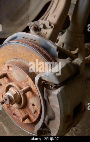 Nahaufnahme von alten und rostigen Scheibenbremsen und Bremssätteln mit Achsschenkel und Aufhängung ohne Rad, Fahrzeugpflege- und Sicherheitskonzept, Fahrzeugwartung Stockfoto