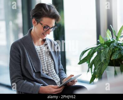 Wenn Sie Ihre Bemühungen wiederholen, maximieren Sie Ihren Erfolg. Eine junge Kreative, die in einem modernen Büro mit einem digitalen Tablet arbeitet. Stockfoto