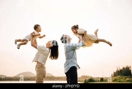 Eine glückliche Familie genießt verspielte Momente auf einem Sommerfeld Stockfoto