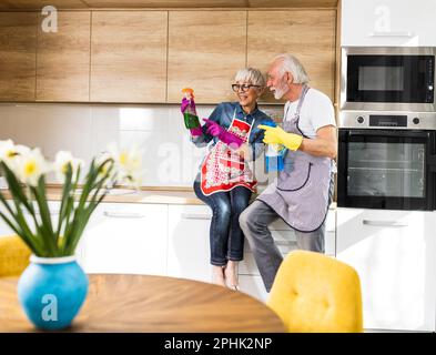 Süßes reifes Paar, das über Reinigungsprodukte in der Küche spricht, während es sich von der Arbeit ausruht Stockfoto
