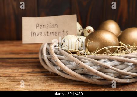 Verschiedene Eier und Karten mit Phrase Pensionsinvestitionen in Nest auf Holztisch, Nahaufnahme Stockfoto
