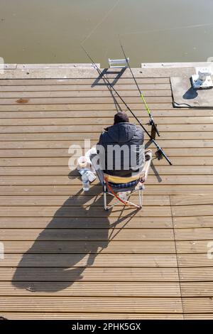 Junger Mann beim Angeln, sitzt am Kanal in Brüssel. Stockfoto