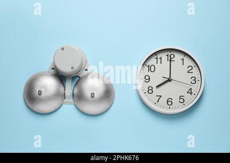 Moderne elektrische Schulglocke und Uhr an hellblauer Wand Stockfoto